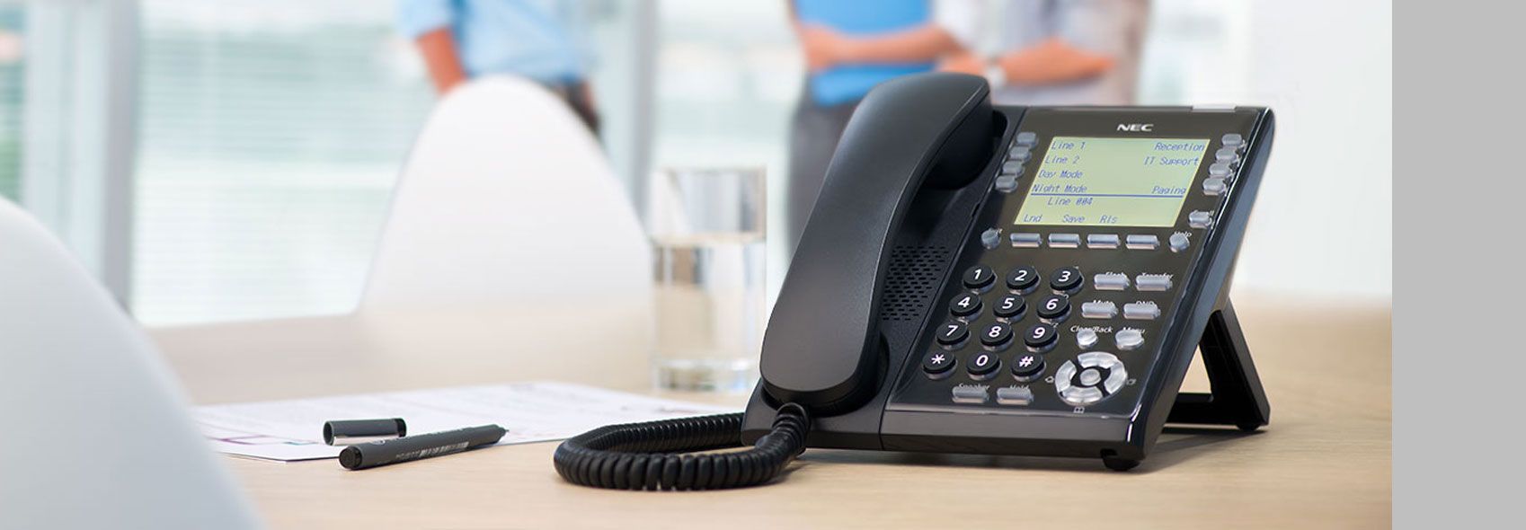 Desk Phone on a Wooden Table in a Bright Office — Pacific Telephone & Data In Cardiff, NSW