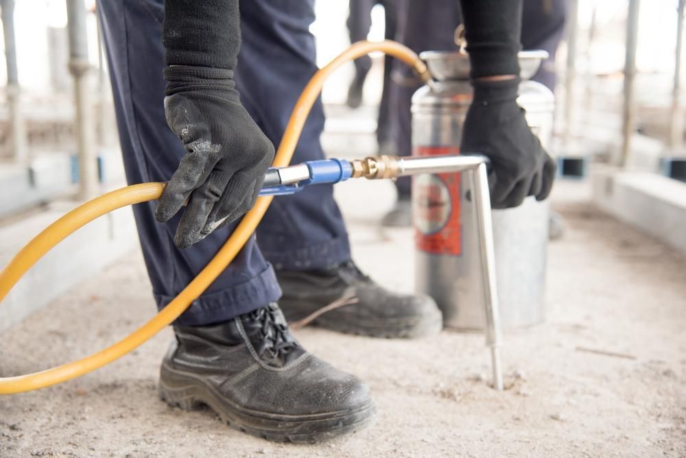 A Person Is Spraying Something with A Hose — Tableland Pest Control in Atherton, QLD