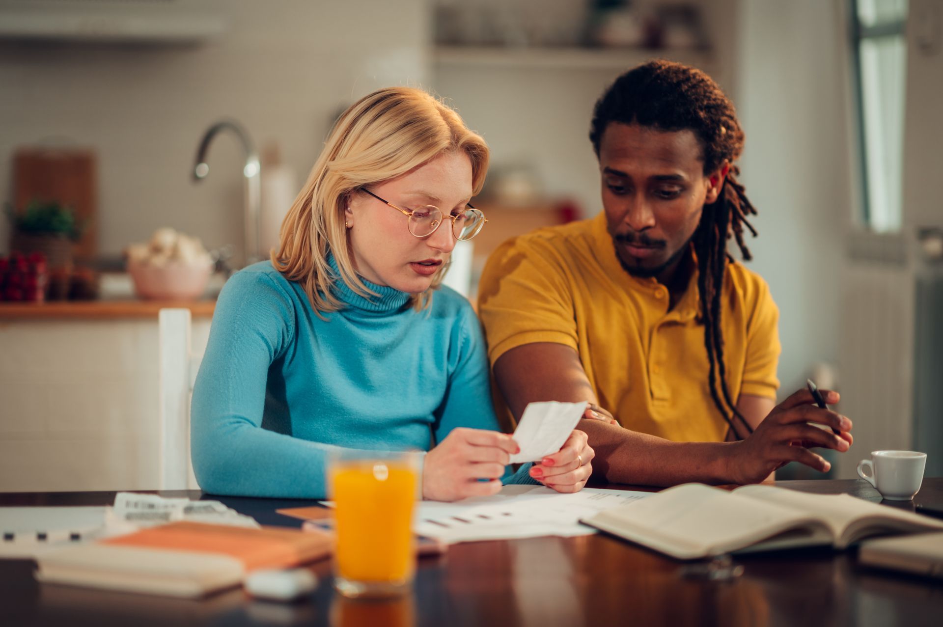 A man and a woman are sitting at a table looking at a piece of paper.