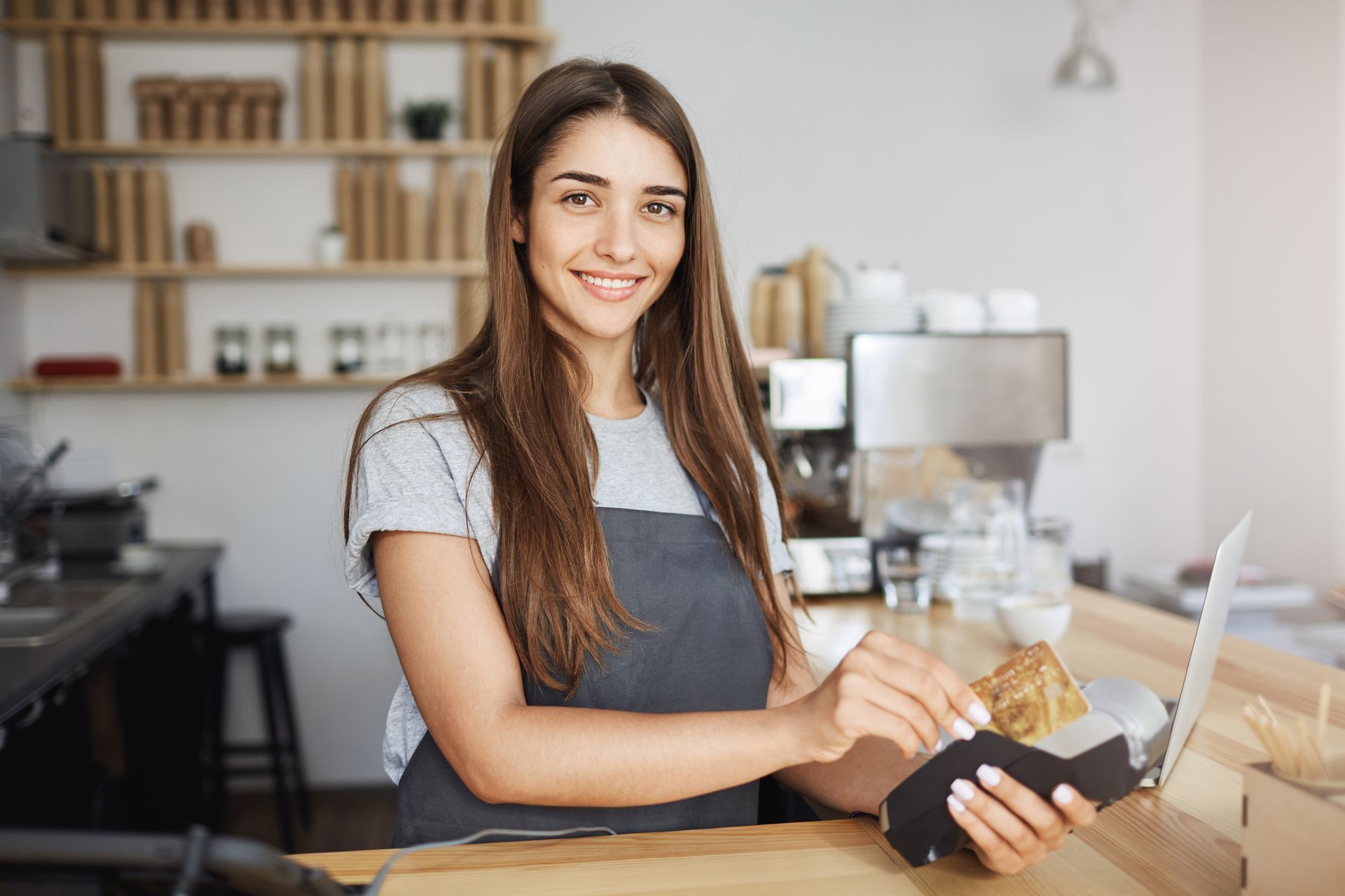 A woman is sitting at a counter in a restaurant holding a credit card and a receipt.