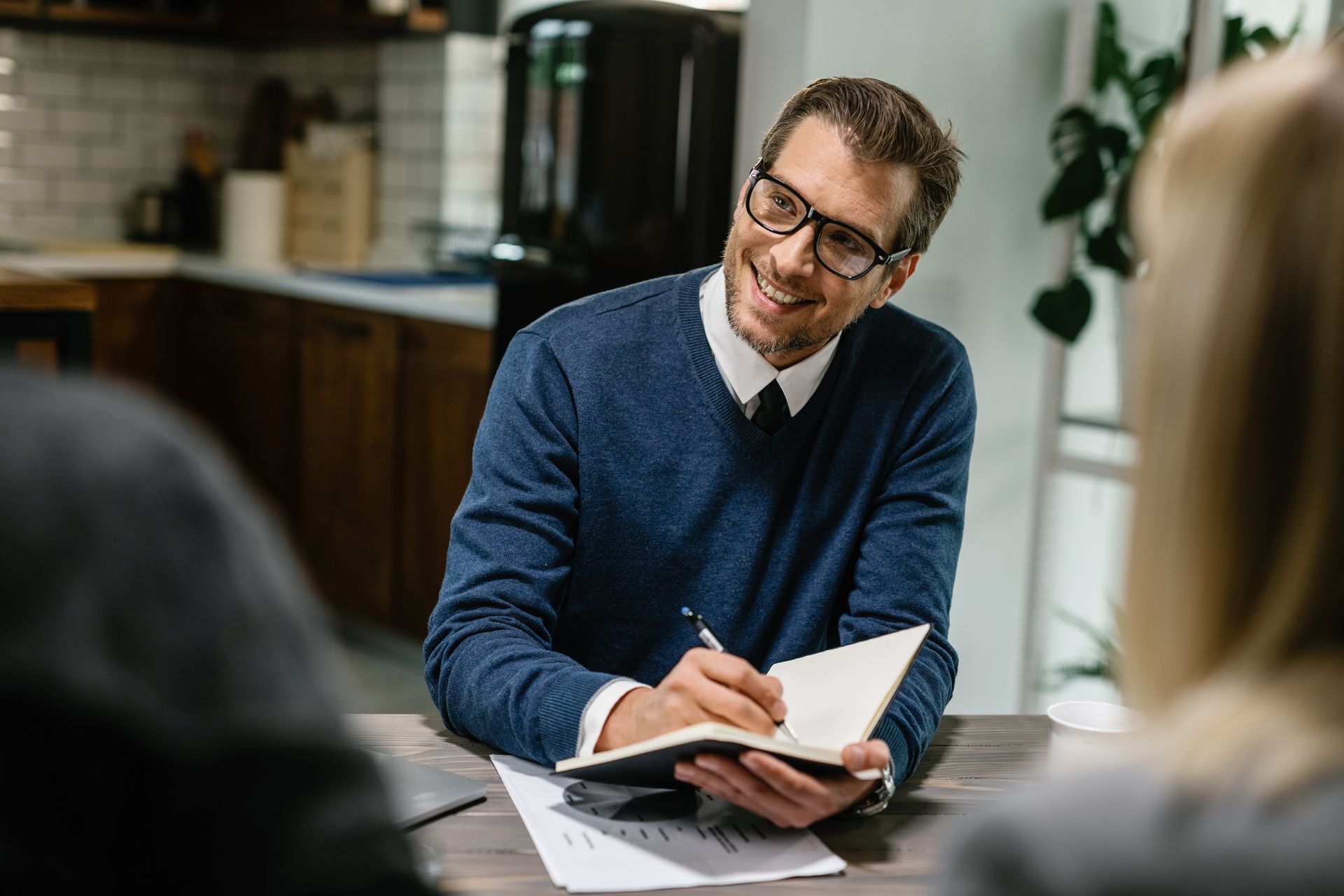 A man is sitting at a table writing in a notebook.
