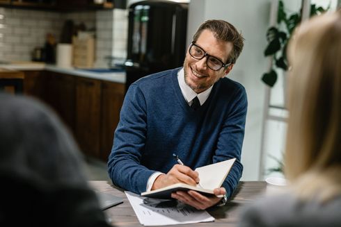 A man is sitting at a table writing in a notebook.