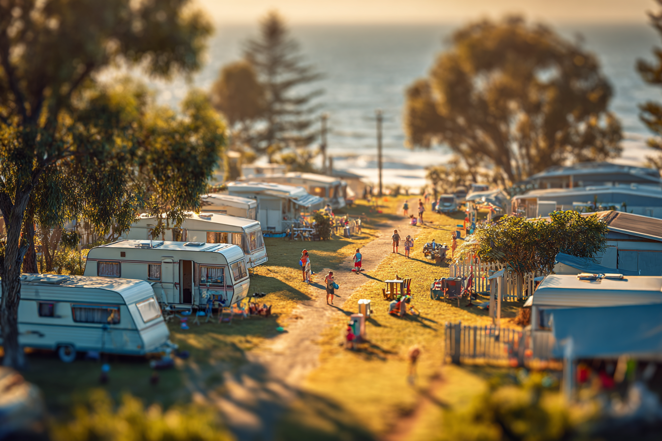 Busy lakeside RV campground with tents, campers, and people near the water at sunset