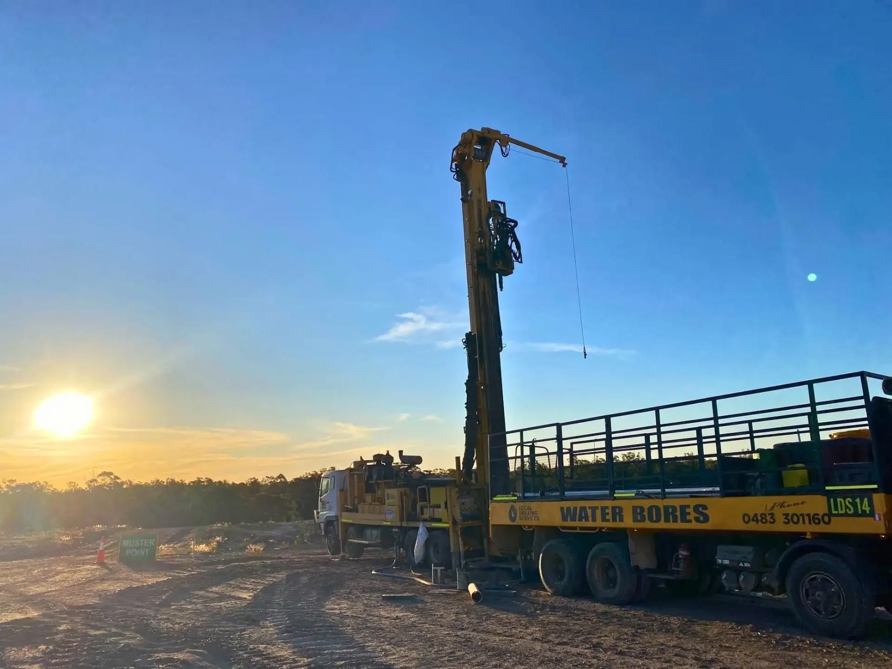 A Water Bore Drilling Truck With Tall Boom at Sunset in a Dirt Field — Local Drilling Services In Yarraman, QLD