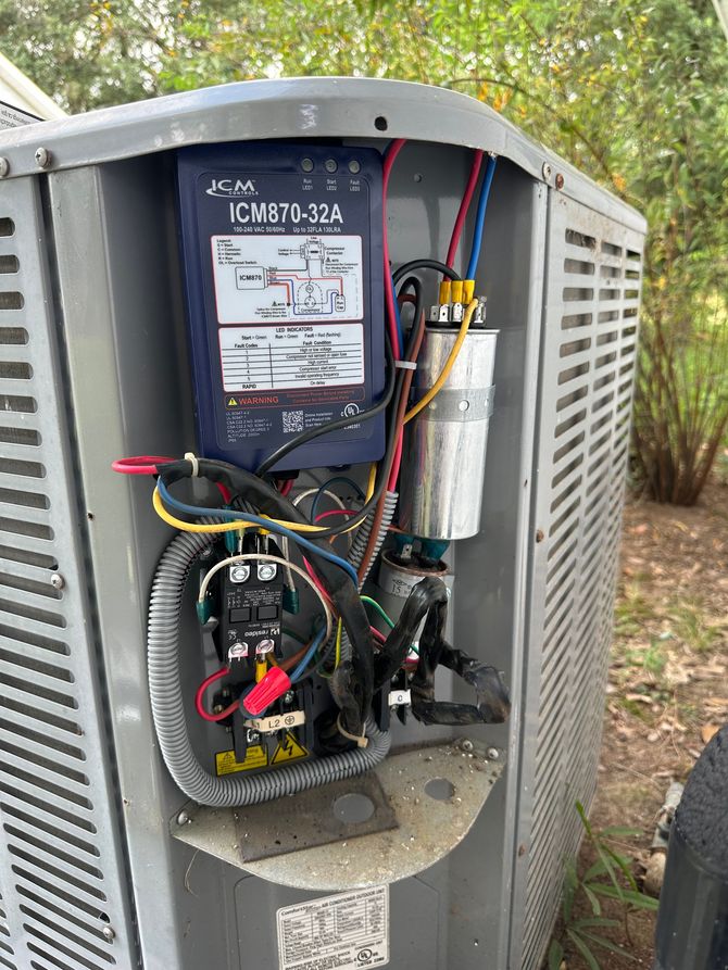 Open HVAC unit with exposed wiring and components outdoors on a metal cabinet