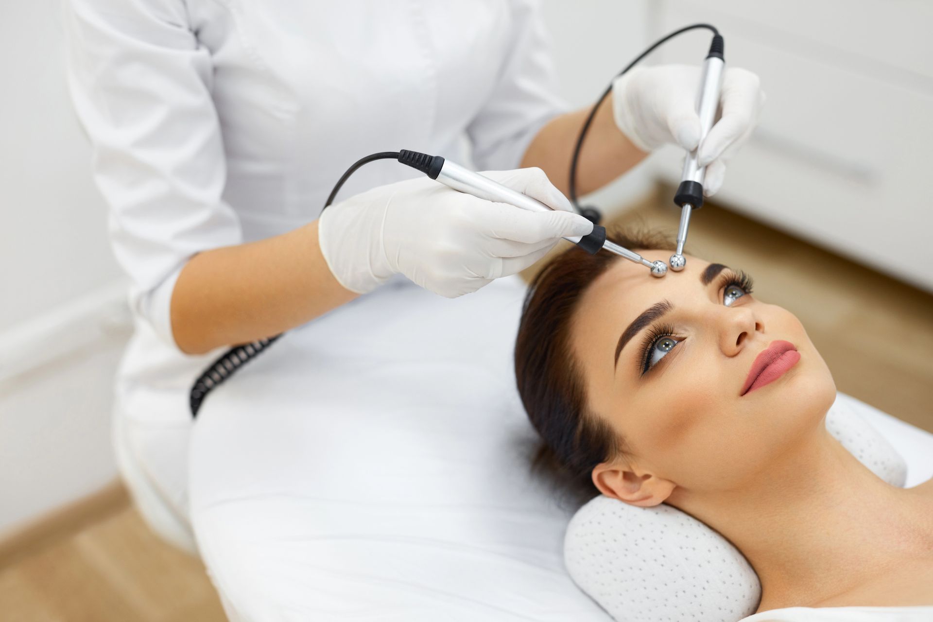 Un profesional con bata médica blanca realiza una terapia facial