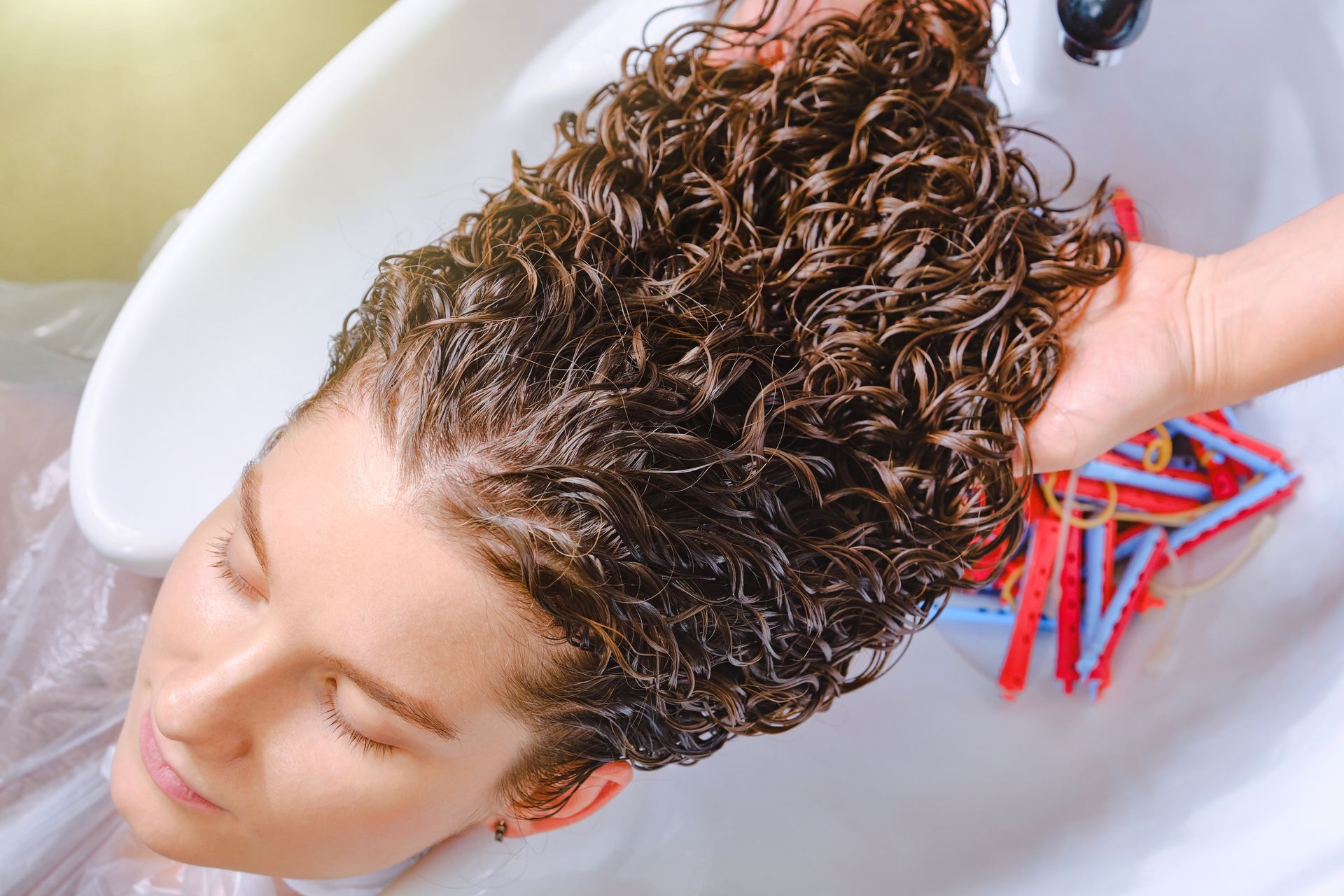 Person With Wet, Curly Hair Being Washed in a Salon Sink — Oh So Blonde Hair Studio in Kawana, QLD