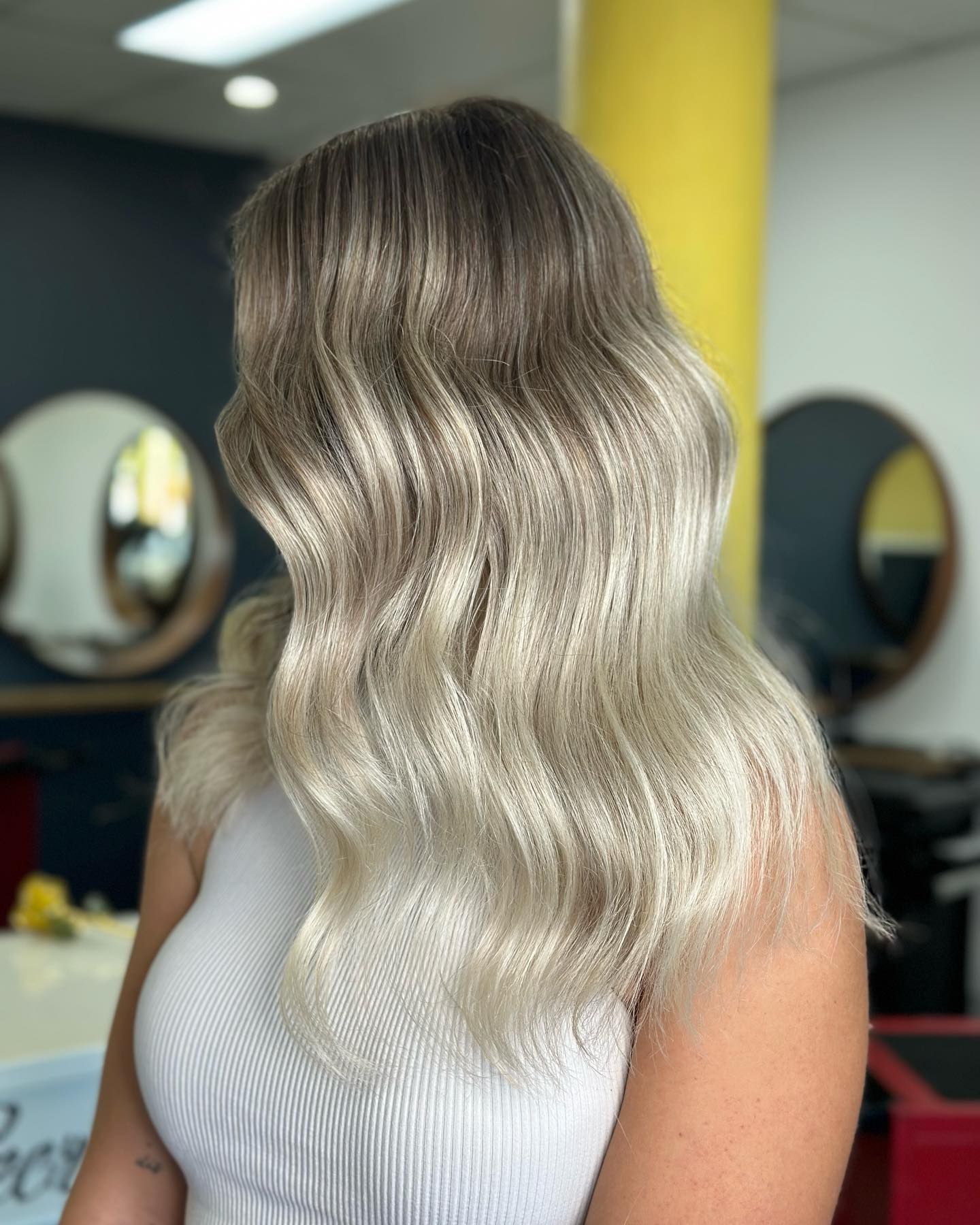 Wavy Blonde Ombré Hair Styled In A Salon, Shown From The Back With A Ribbed White Top — Oh So Blonde Hair Studio in Kawana, QLD
