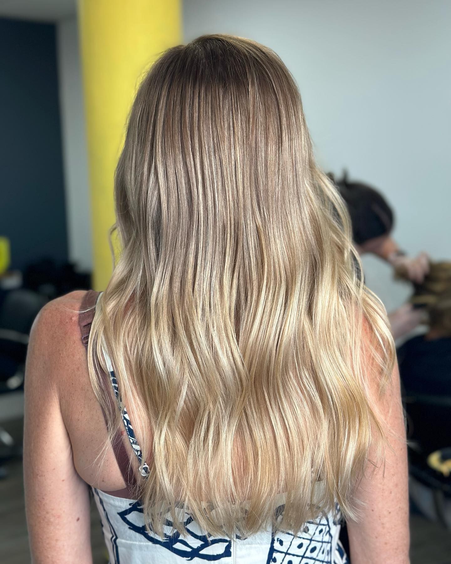 Back View Of A Person With Long Blonde Hair In A Patterned Top Indoors — Oh So Blonde Hair Studio in Kawana, QLD