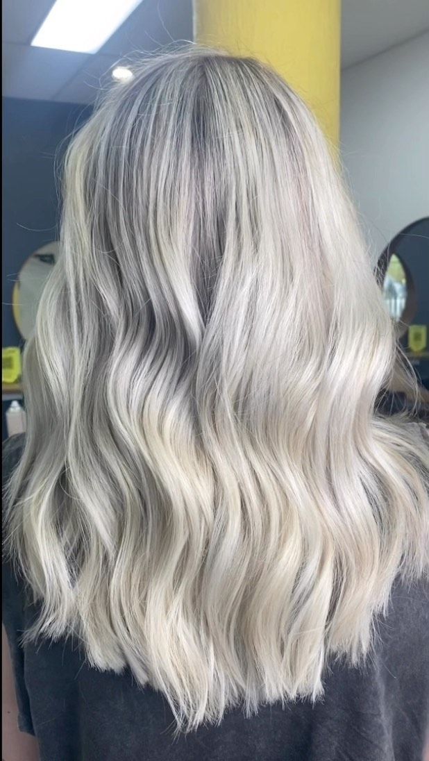Long Wavy Platinum-blonde Hair With Dark Roots, Shown From The Back Against A Yellow Wall — Oh So Blonde Hair Studio in Kawana, QLD