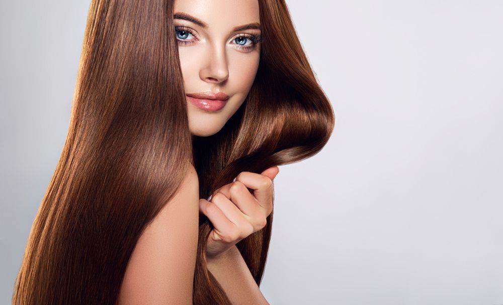 Woman With Long, Shiny Brown Hair Holding Strands — Oh So Blonde Hair Studio in Buddina, QLD