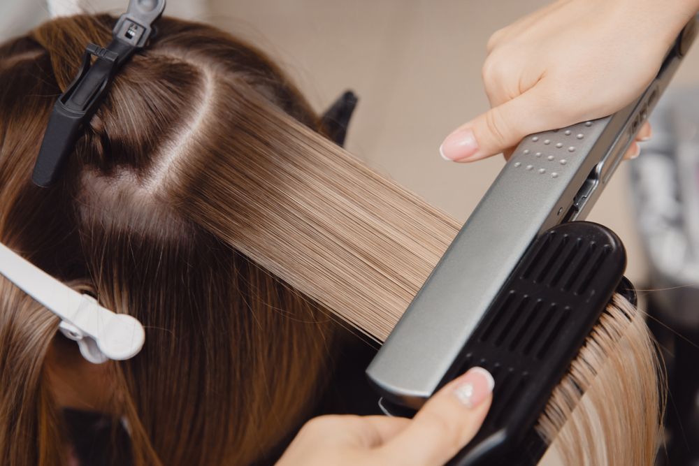 Hair Being Straightened With a Flat Iron — Oh So Blonde Hair Studio in Buddina, QLD