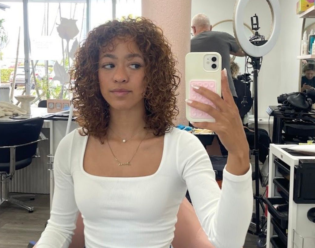 Woman Taking A Mirror Selfie In A Salon, Wearing A White Top With Curly Hair — Oh So Blonde Hair Studio in Kawana, QLD