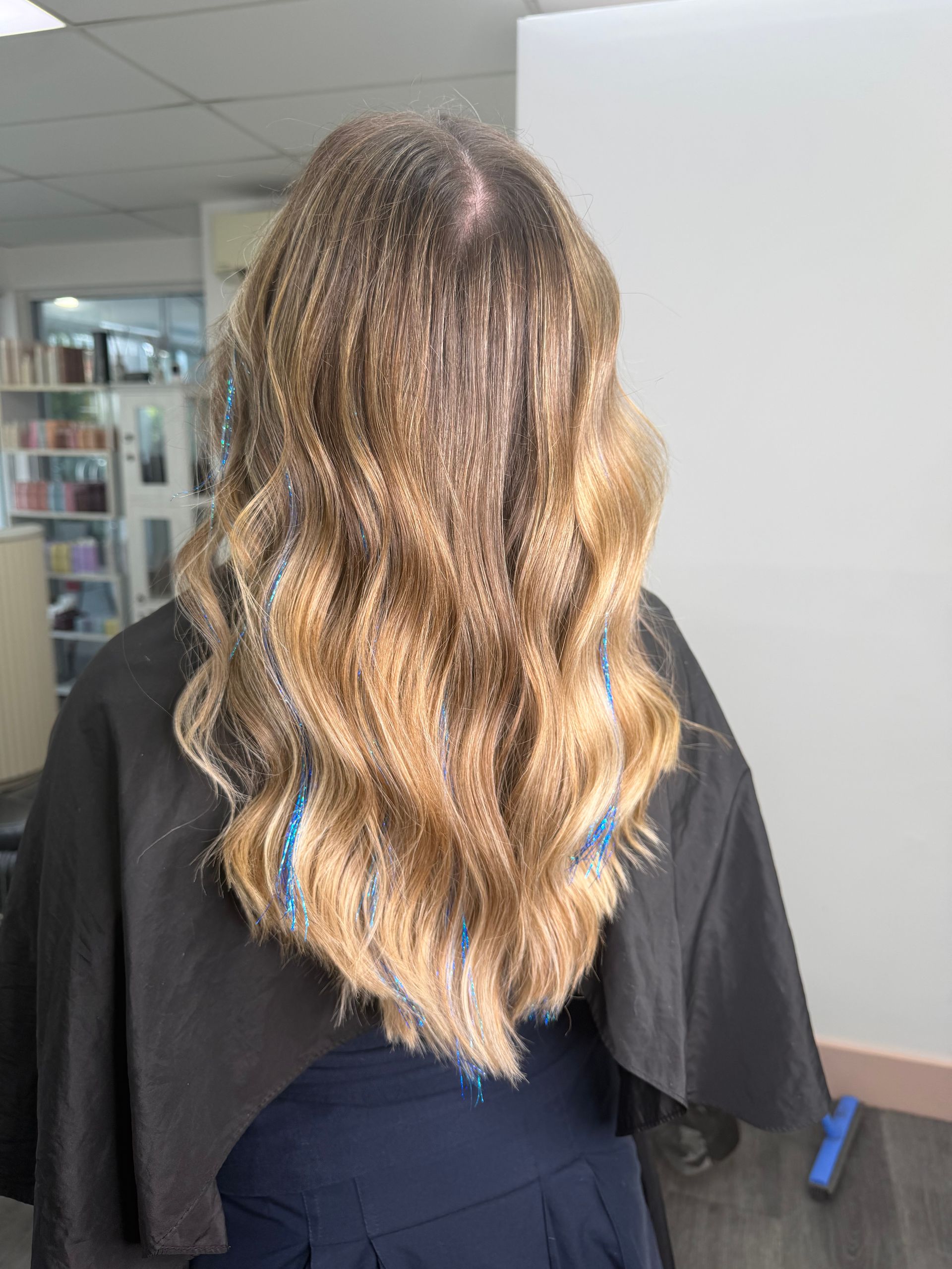 Back View Of Long Wavy Blonde Hair With Blue Streaks In A Salon Interior — Oh So Blonde Hair Studio in Kawana, QLD
