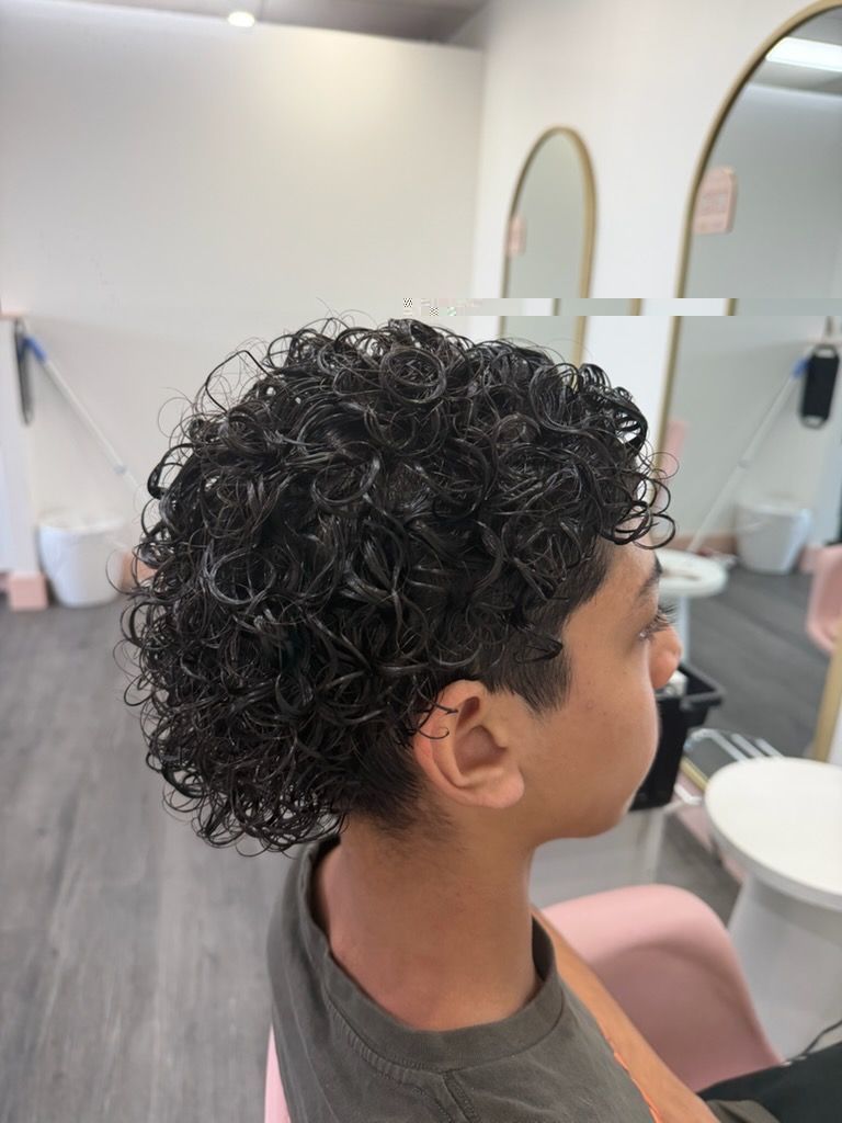 Side Profile Of A Person With Curly Dark Hair In A Modern Salon, With Mirrors And Styling Chairs In The Background — Oh So Blonde Hair Studio in Buddina, QLD