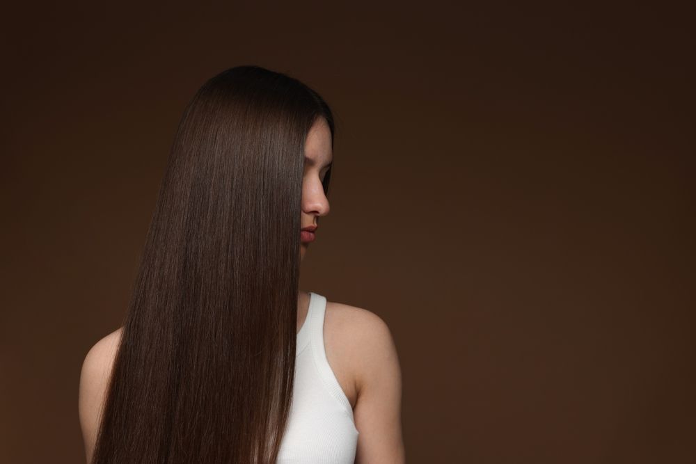 Woman With Long Straight Brown Hair, Turned Sideways Against A Dark Brown Background — Oh So Blonde Hair Studio in Buddina, QLD