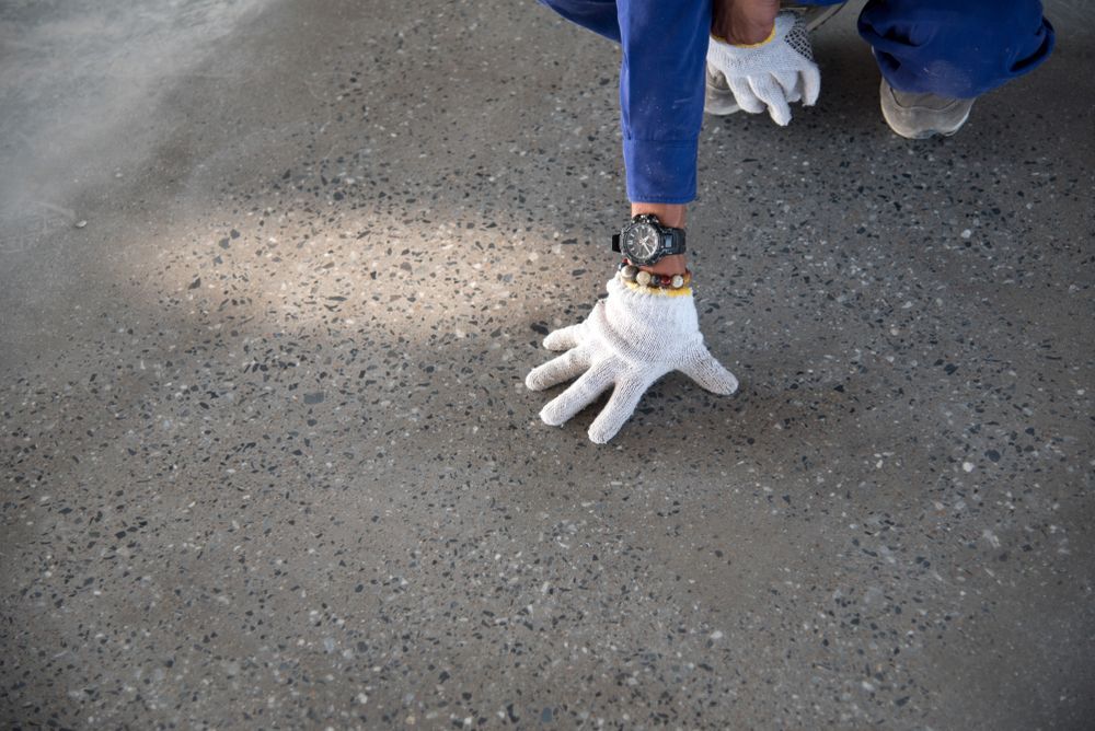 A person wearing white gloves and a watch is kneeling on the ground — Let's Paint & Decorate Pty Ltd in Oak Flats, NSW