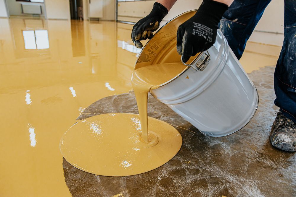 A person is pouring yellow paint into a bucket — Let's Paint & Decorate Pty Ltd in Oak Flats, NSW