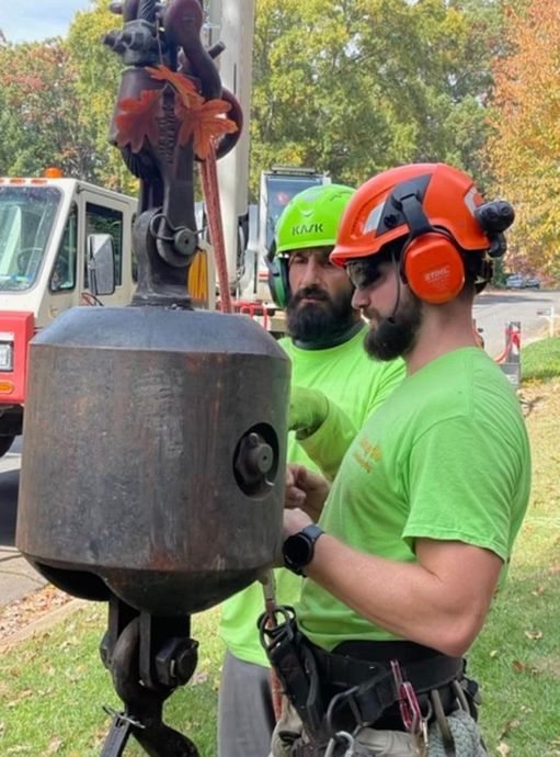 Two workers in neon shirts and hard hats operating a suspended concrete bucket outdoors