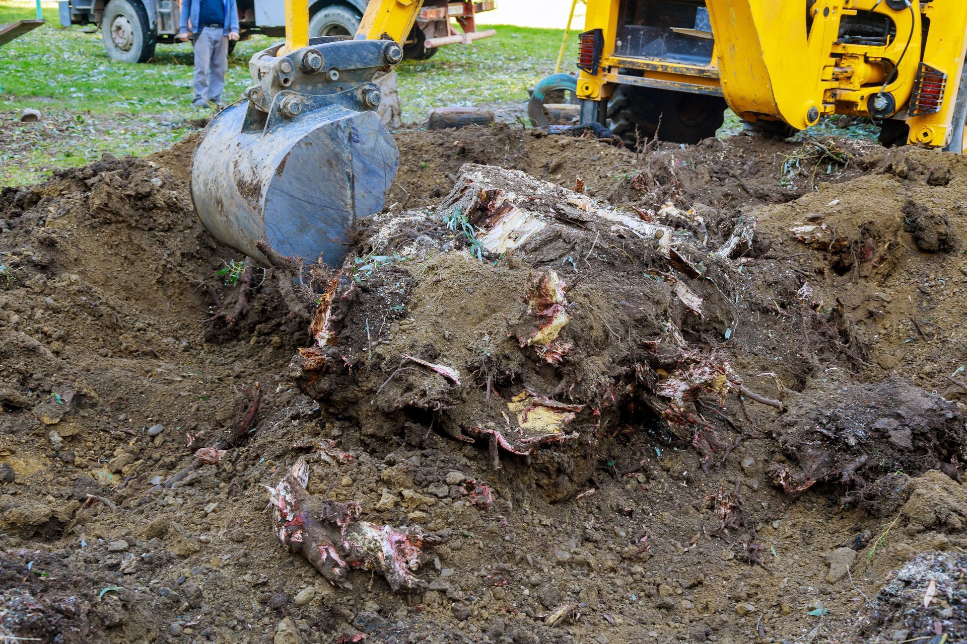Excavator bucket digging through a muddy pile of debris at a construction site