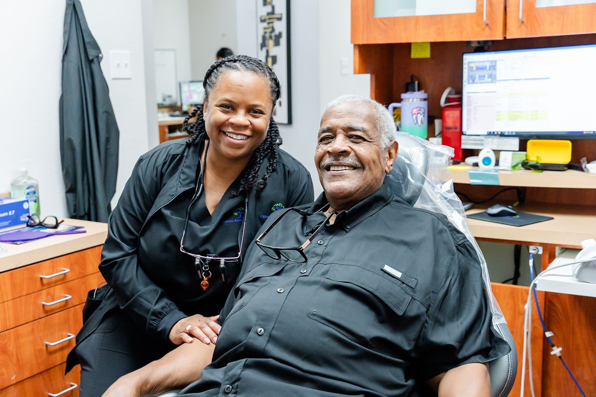 A woman is sitting in a dental chair with her hand on her face.