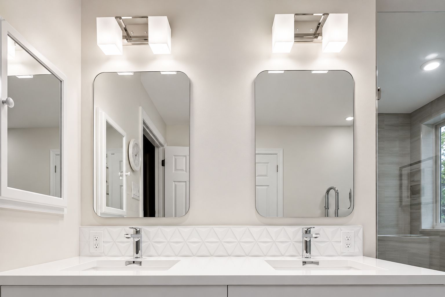 Bright modern bathroom vanity with double mirrors, wall lights, and white countertops
