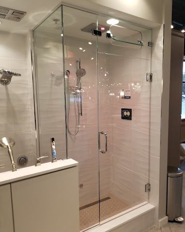 A bathroom with a walk in shower with a glass door.