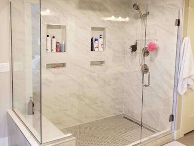 A bathroom with a walk in shower with a glass door.