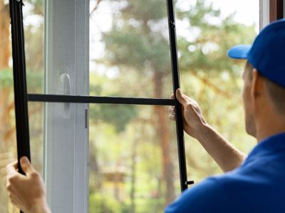 a man is installing a mosquito screen on a window .