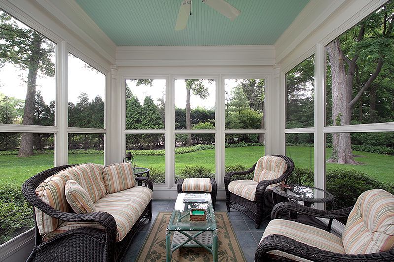 A screened in porch with furniture and a ceiling fan