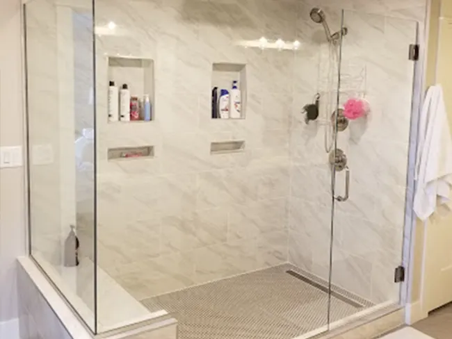 A bathroom with a walk in shower with a glass door.