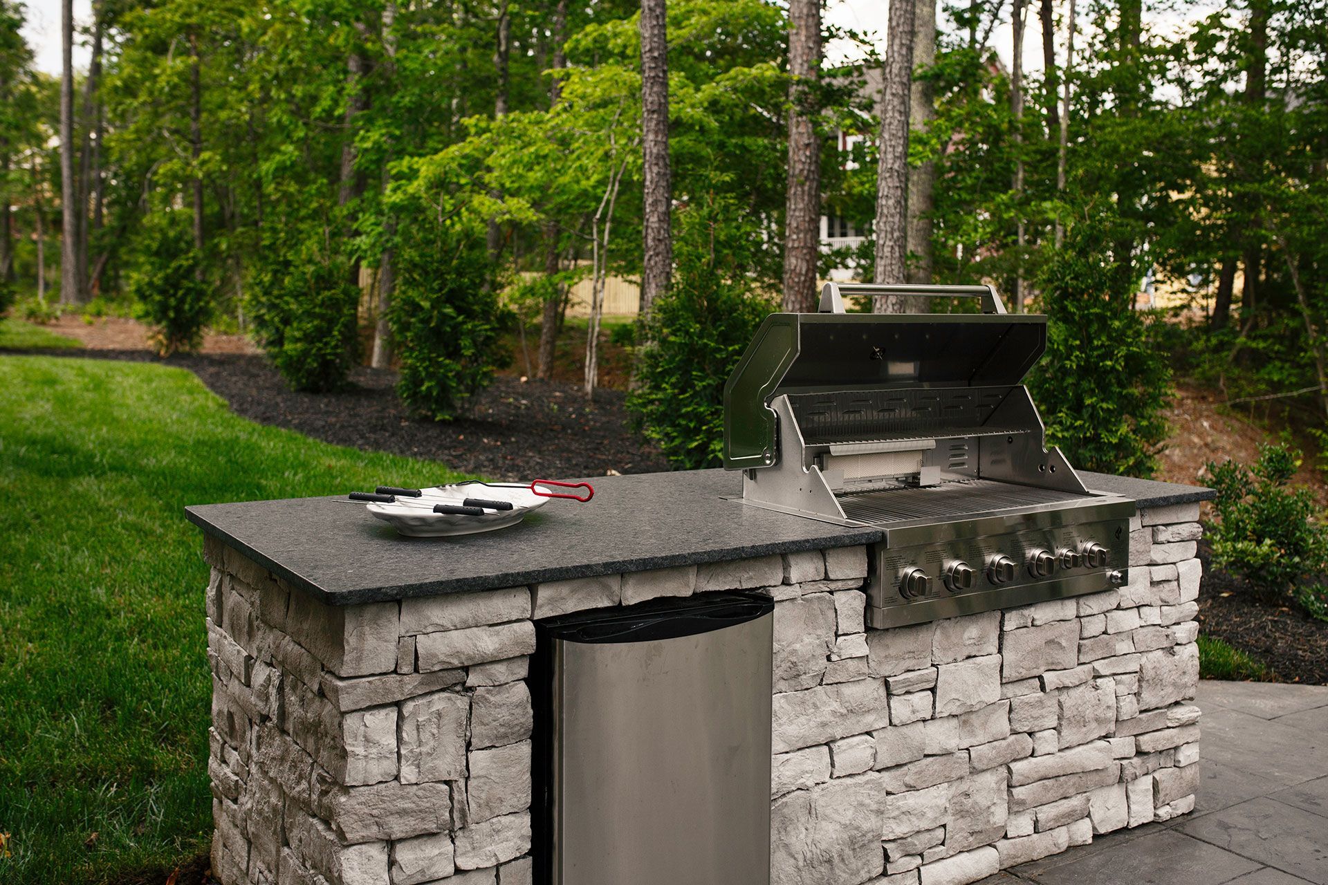 Stone outdoor grill and counter in a green park with trees in the background