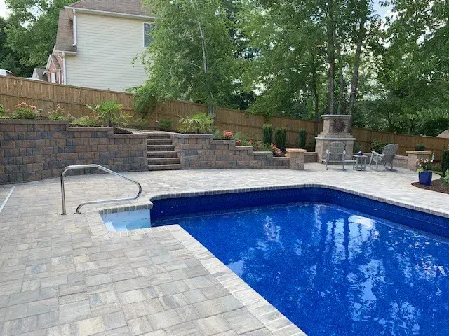 A large swimming pool is surrounded by a brick patio.