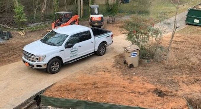 White pickup truck on a dirt road beside a cardboard box and trees in a rural area
