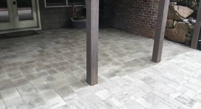 Patio with tiled floor, wooden posts, and stone wall near a doorway