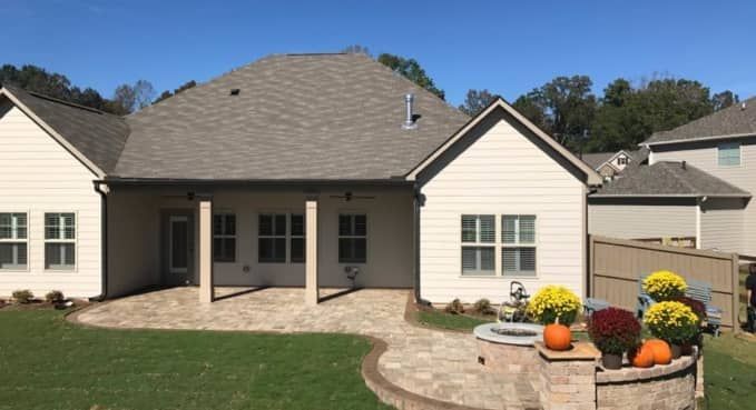 Single-story beige house with a covered patio, brick walkway, and flower planter in the front yard