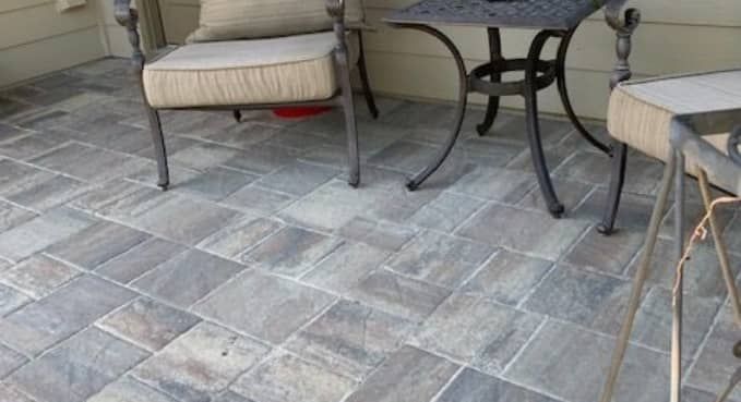 Stone patio with cushioned chairs and a small round table under an outdoor overhang