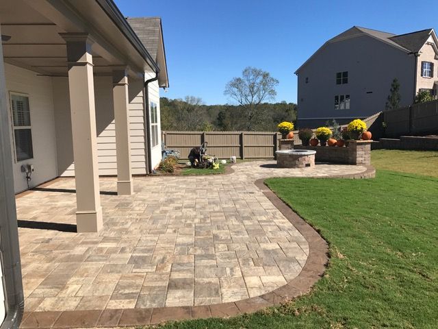 Back patio with stone pavers, lawn, and raised flower beds on a sunny day