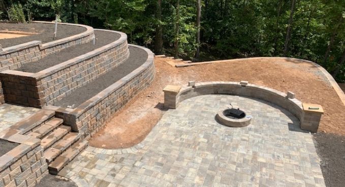 Stone patio and curved retaining walls around a circular fire pit in a landscaped backyard