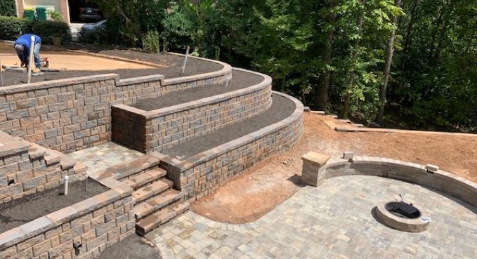 Curved stone retaining wall and steps around a landscaped patio under construction