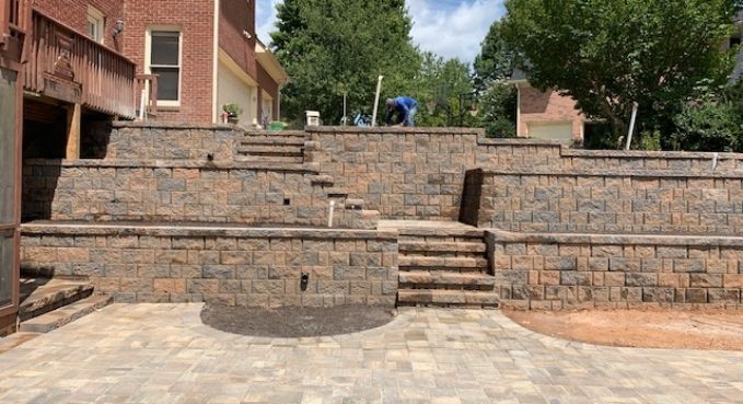Outdoor stone amphitheater with tiered seating and central steps beside brick buildings and trees