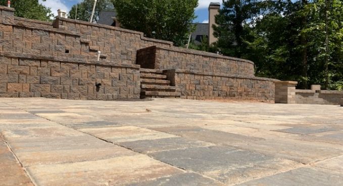 Stone steps and tiered retaining wall in an empty outdoor plaza with trees in the background