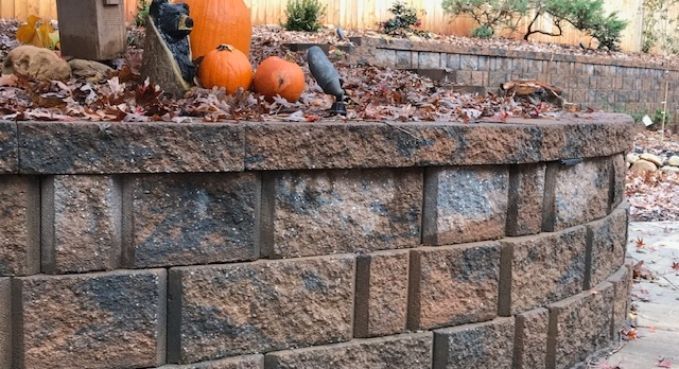 Stone retaining wall with orange pumpkins and fall decor on top