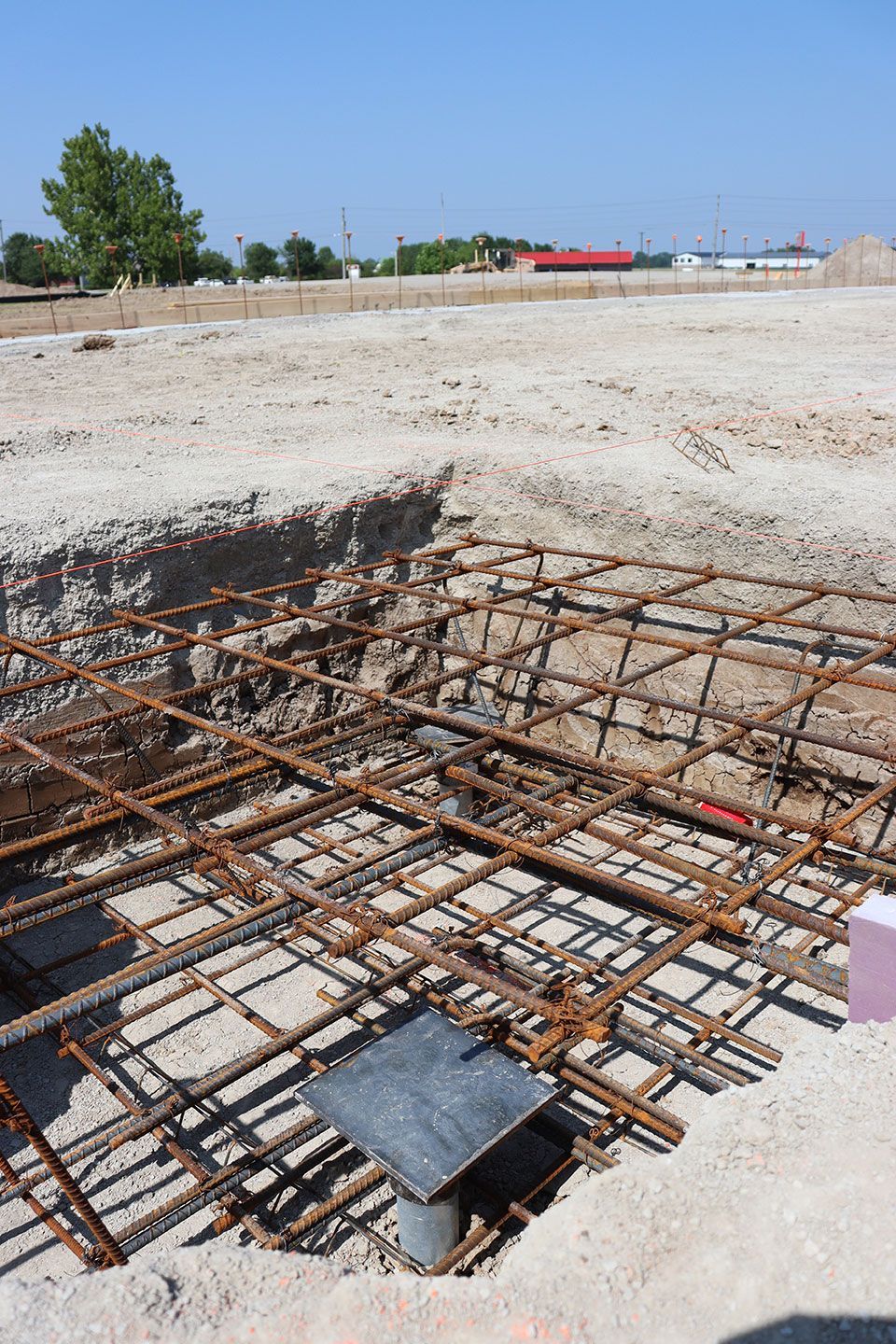 Construction site with exposed rebar foundation pit under a clear blue sky