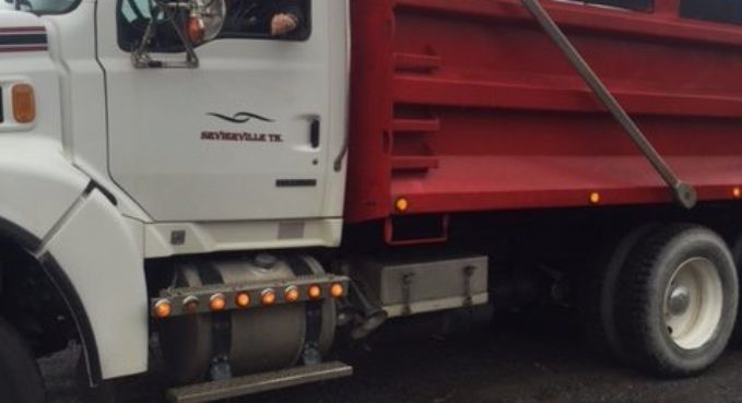 White and red cargo truck side view with cab door and rear wheel visible.