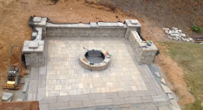 Stone patio with a circular fire pit and built-in bench seating, viewed from above.