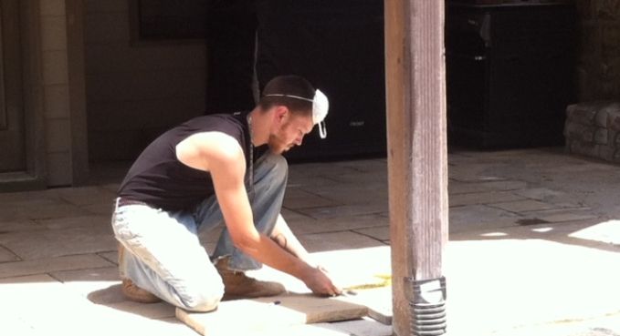 Person kneeling and smoothing a concrete floor in a shaded indoor space