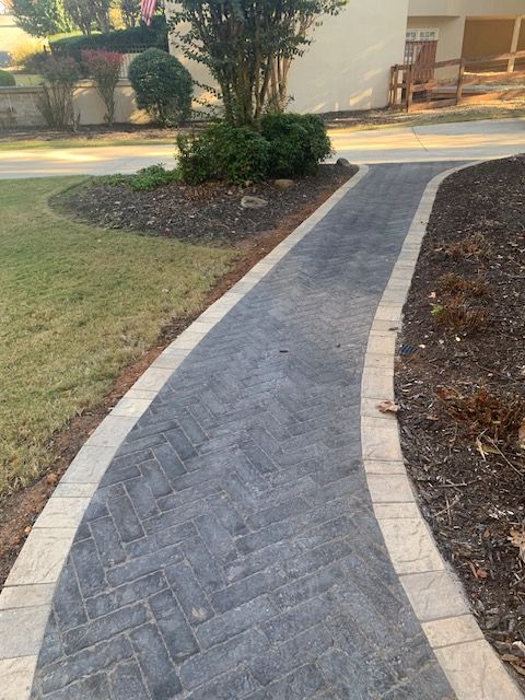 Brick walkway curving through a landscaped yard with grass and mulch beds