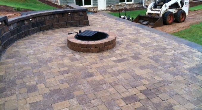 Paved patio with a circular fire pit in the center and a small white utility vehicle in the background