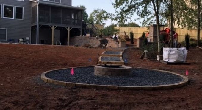 Construction site with a circular in-ground pool, dirt lot, and house in the background